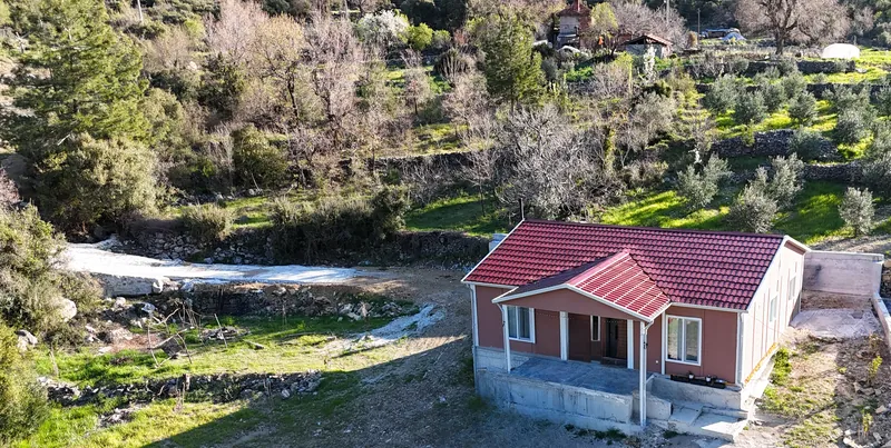 Wider aerial view of the house among olive terraces and pine-covered hills
