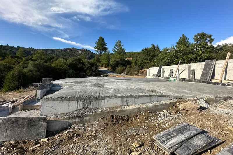 Freshly poured reinforced-concrete foundation slab with a retaining wall behind it