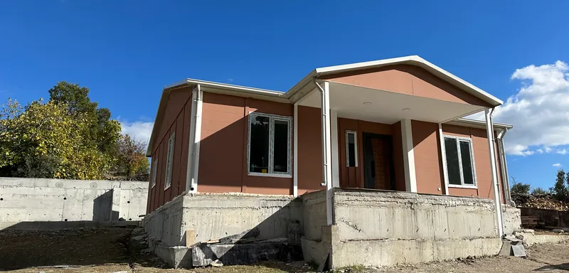 Front of the new house with terracotta panel walls, white trim and a covered porch on a raised concrete base